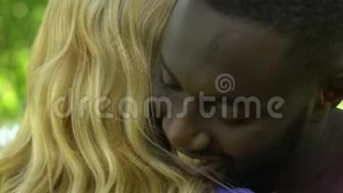 快乐的非裔美国人拥抱他漂亮的金发女友，闭上嘴