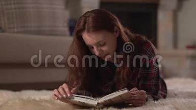 可爱的女人，穿着格子衬衫，躺在蓬松的地毯上，近距离阅读这本<strong>书</strong>。 女士<strong>翻页</strong>，微笑，放松