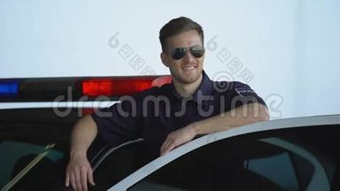 戴墨镜的友好警察站在汽车旁微笑，法律和秩序