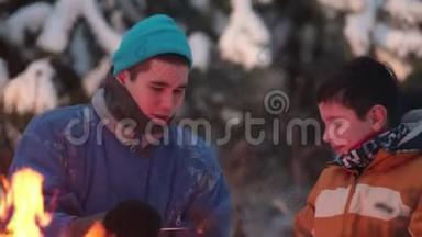 冬季森林。 年轻人和他的<strong>弟弟</strong>坐在火边聊天