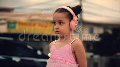 一个可爱的孩子站在路边的肖像，一个穿着<strong>粉色</strong>连衣裙和<strong>粉色</strong>耳机的可爱的小可爱女孩