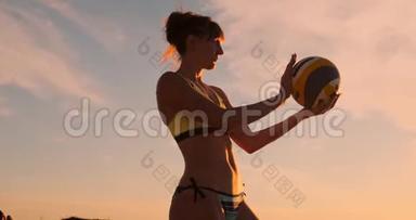 一位身穿比基尼、日落时带球的美女正准备在沙滩排球比赛中发球跳跃