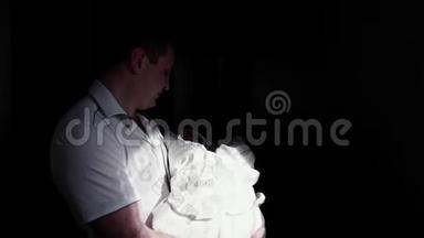 父亲怀里抱着一个熟睡的小儿子，光落在他身上