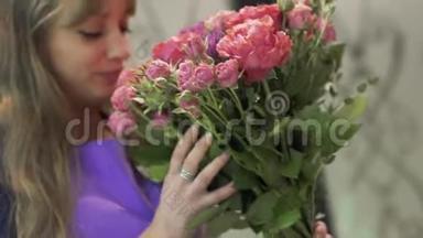年轻女子花店闻着一束美丽的花。 在花店里捧着一束花的漂亮女孩