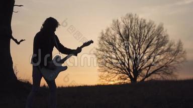 日落时分，人们在靠近树的田野里弹着电<strong>吉他</strong>，唱歌。 <strong>剪影</strong>
