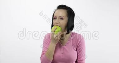 年轻漂亮的女人在白色背景下吃着大而多汁的绿苹果