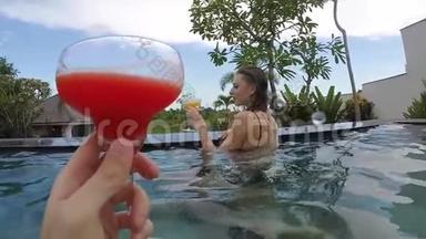 年轻可爱的一对夫妇在热带度假别墅的游<strong>泳池</strong>里碰杯。