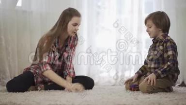 肖像姐姐和弟弟一起玩，<strong>坐在地板上</strong>毛茸茸的地毯<strong>上</strong>。 那个男孩在玩