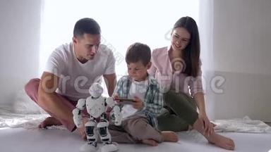 现代玩具，小男孩和爸爸妈妈一起玩人形机器人<strong>遥控</strong>智能<strong>手机</strong>坐在地上