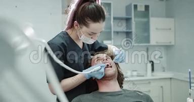 在一个现代诊所的房间里，牙列为年轻的病人做<strong>口腔</strong>卫生程序，在牙科室。 4k