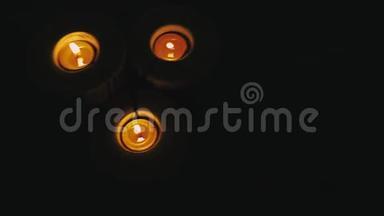 木制烛台上的三根蜡烛在黑暗中燃烧。 空中飞盘近射闪烁的火焰