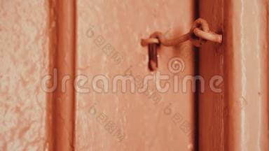 晚上，一个男人`手打开一扇锁在钩子上的房子里的木门。 白炽灯光。 木门是粉刷过的