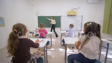 孩子们上学，小老师女靠近黑板，在教室的<strong>课桌</strong>上给孩子们上认知课