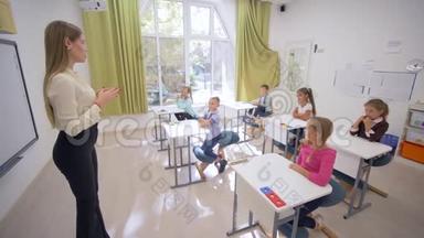 在学校的课堂教学中，女教师在课桌旁与可爱的小学生交谈