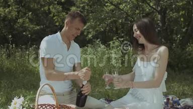 一对夫妇在野餐时把香槟倒进玻璃杯