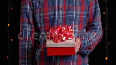 带黑背景礼盒的男孩。 新年快乐、圣诞快乐、情人节`礼品盒