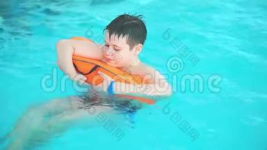 少年在游泳池里游泳，<strong>紧紧</strong>抓住橙色的花车。
