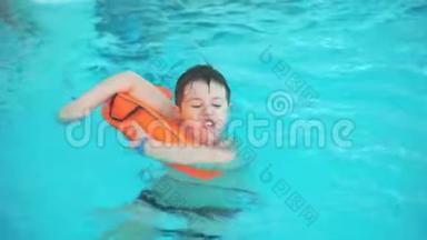 少年在游泳池里游泳，紧紧抓住橙色的花车。