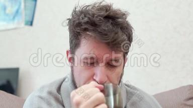 男人喝柠檬和咳嗽的茶。 他感冒，头痛，发烧，发冷