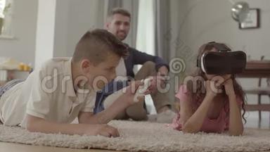 男孩和女孩用虚拟现实眼镜躺在毛茸茸的<strong>地毯</strong>上，父亲坐在<strong>地毯</strong>上