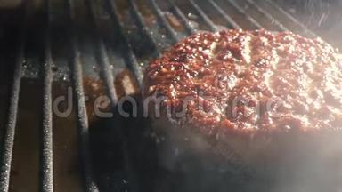 烟雾从烤架上的切块上方升起. 美味的牛肉汉堡在烤架上翻转