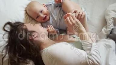 妈妈和宝宝早上在床上。 女人和孩子看着镜头微笑。 妈妈`天，妈妈快乐