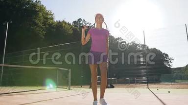 可爱的微笑女孩，网球拍在网球场上行走。