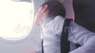 男孩在飞机上飞行时<strong>看</strong>着<strong>窗外</strong>。