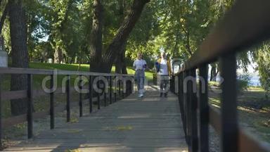 积极的退休人员在公园里散步，带着瑜伽垫和水瓶，锻炼身体