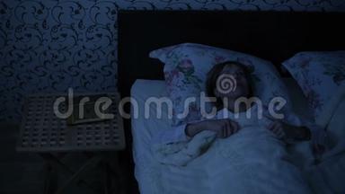 一个女孩在晚上醒来时的平均镜头是下床。 低调。 美国之夜的影响.. 寒冷的夜晚