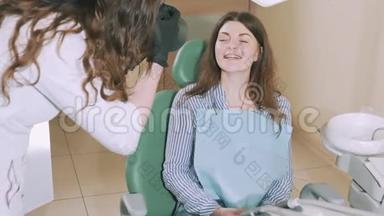 牙医办公室里一个漂亮迷人的年轻女孩正灿烂地微笑着，展示着牙医的成果