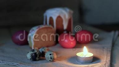 贺卡的背景：特写燃烧的蜡烛，背景中五颜六色的复活节彩蛋和切成两半的复活节蛋糕