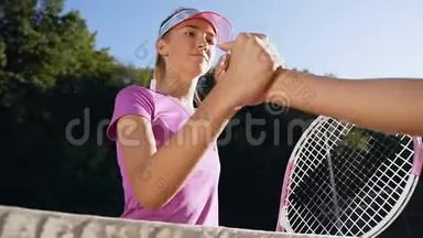 一个可爱的女孩在网球场上和另一个女孩握手的肖像。
