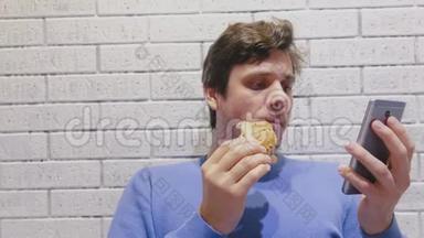 男人在咖啡馆里吃汉堡包，用手机看视频。