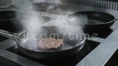 厨师将生牛肉切块缓慢地放入餐厅厨房的热锅中，用烟熏和熏烤牛肉