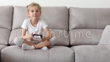女孩在电子游戏机中玩，使用操纵杆控制器。 快乐的金发女孩玩电子游戏。