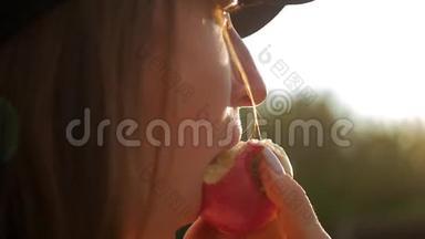 美丽的女孩在日落时吃一个<strong>红苹果</strong>。 少女带着<strong>红苹果</strong>，慢动作..