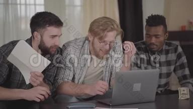 两个白种人和一个非裔美国人坐在笔记本电脑前在家休息。 多元文化公司