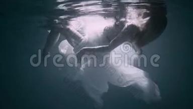 年轻的女人在水下，她穿着一件白色的裙子。
