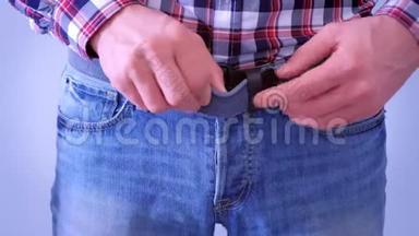男人用手解开皮带和解开牛仔裤纽扣。