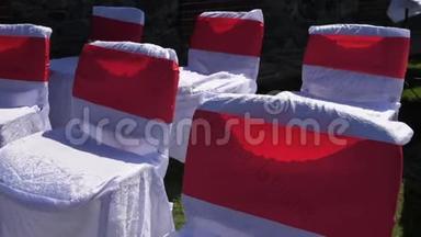 装饰着白色和红色布的椅子站在绿草的草坪上。