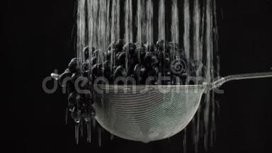 在视频中，我们看到葡萄在筛子中，水从顶部开始下降，然后停止，然后重新开始，黑色的背景。