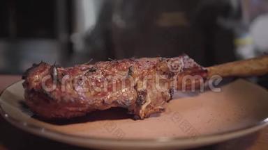 在餐厅的厨房桌子上，一个盘子上，骨头上的烤肉、美味多汁的肉片特写。