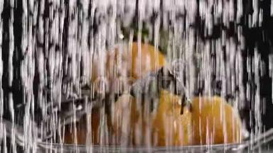 在视频中，我们看到橘子，它们是折叠的，然后水开始从顶部落下，黑色的背景。