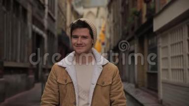 一位年轻时尚的帅哥在欧洲一个古老城镇的街道上对着镜头微笑的肖像。