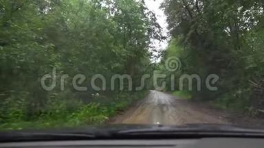 下雨时驾驶汽车行驶在森林的土路上。 交通<strong>恶劣</strong>的<strong>天气</strong>状况。 从小屋看视角