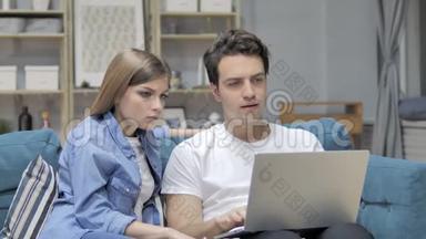 沮丧不快乐的年轻夫妇面对笔记本电脑的损失