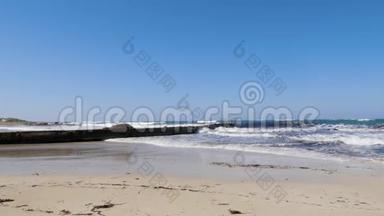 在阳光明媚的多风天气里，强烈的海浪拍打着码头和沙滩。 塞浦路斯海滩暴风雨天气。 慢动作