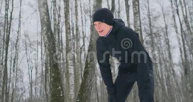 一个年轻人在冬天的森林里晨跑，累了，停下来喘<strong>口气</strong>。 他恢复了体力