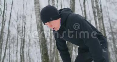 一个年轻人在冬天的森林里晨跑，累了，停下来休息，继续跑。 他恢复了<strong>体力</strong>